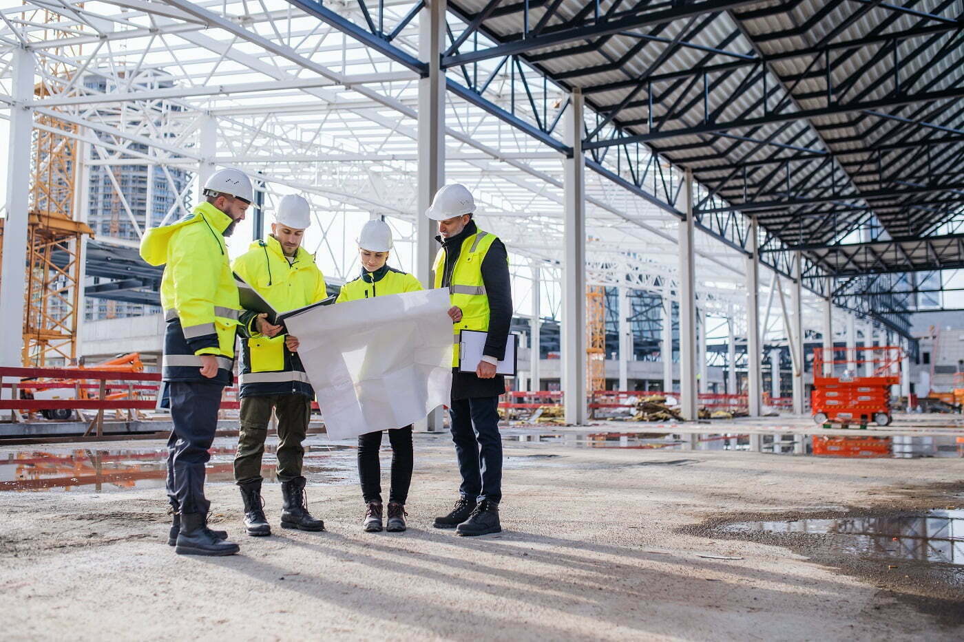 Rakentajat huomioliiveissä ja kypärissä käyvät läpi rakennussuunnitelmaa työmaalla retta