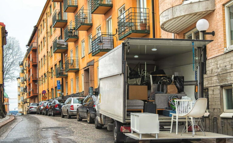 Kuvassa lastattu muuttoauto kerrostaloasuntojen edessä.