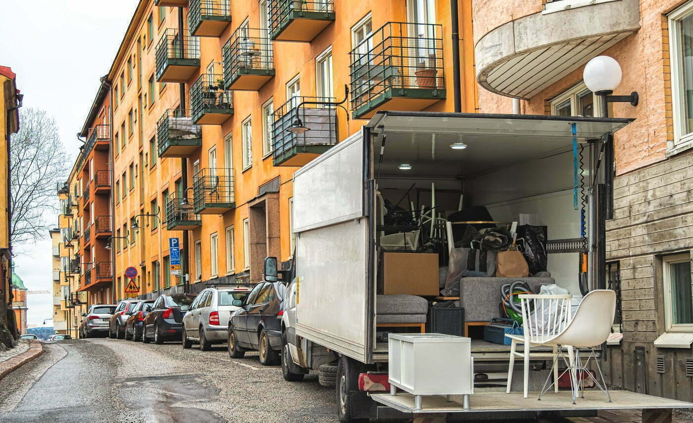 Kuvassa lastattu muuttoauto kerrostaloasuntojen edessä.